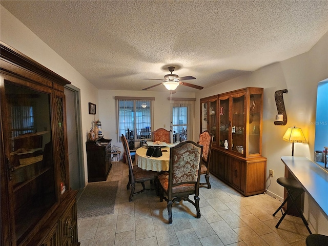 dining space featuring ceiling fan, baseboards, and a textured ceiling