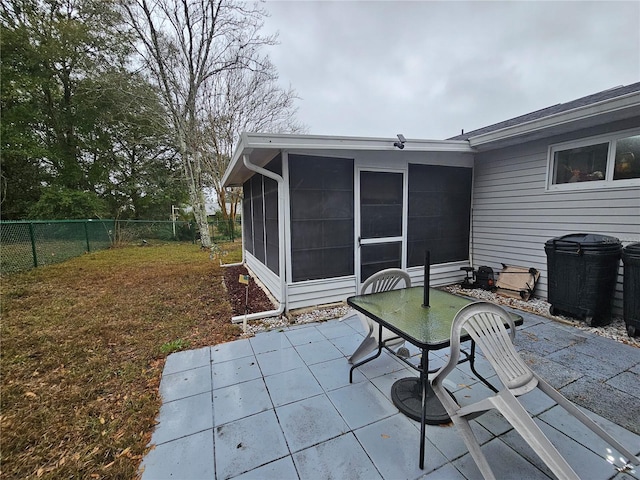 view of patio / terrace featuring outdoor dining space, fence, and a sunroom