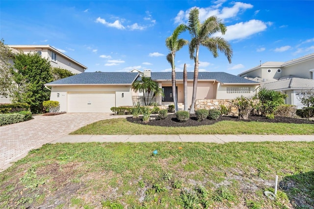 ranch-style house with a front yard, an attached garage, and stucco siding