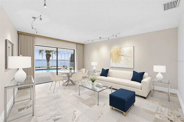 living room with track lighting, visible vents, a textured ceiling, and baseboards