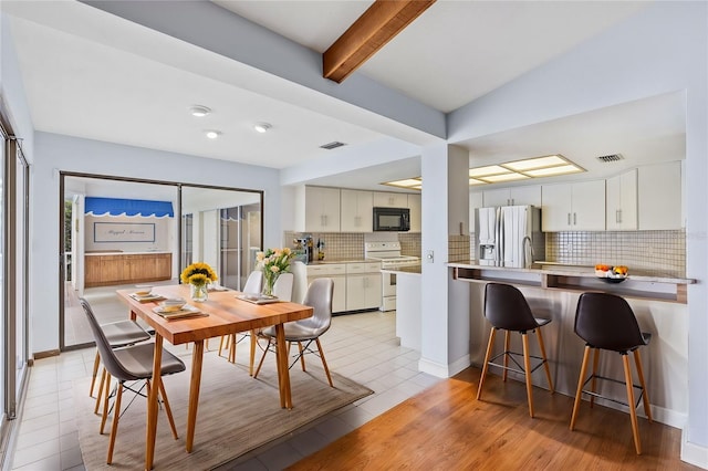 dining area with beam ceiling, visible vents, baseboards, and light tile patterned floors