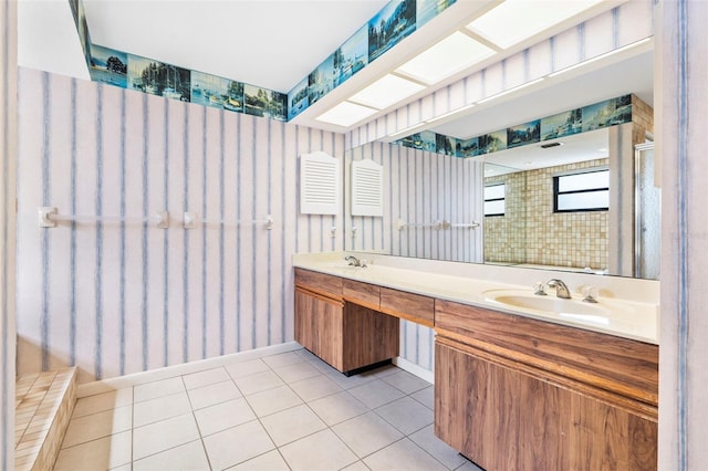 bathroom with a skylight, a sink, a tile shower, and tile patterned floors