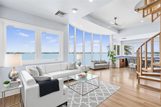 living area with recessed lighting, visible vents, a water view, wood finished floors, and stairs