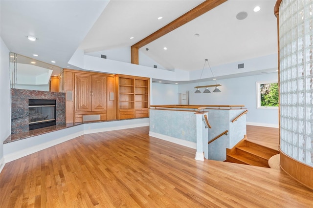 unfurnished living room with visible vents, baseboards, a premium fireplace, light wood-type flooring, and beam ceiling