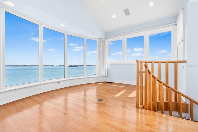 empty room featuring recessed lighting, visible vents, a water view, and wood finished floors