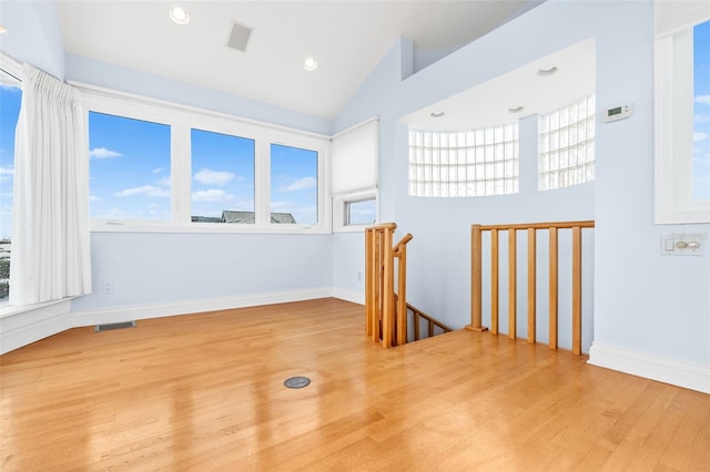 spare room with lofted ceiling, recessed lighting, wood finished floors, visible vents, and baseboards