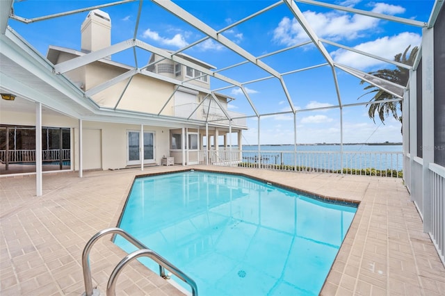 outdoor pool featuring glass enclosure, a patio area, and a water view