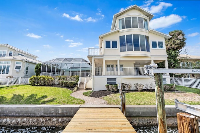 rear view of house featuring a water view, fence, a lawn, and stucco siding