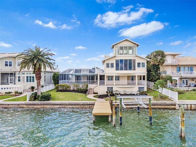 view of dock with a water view, boat lift, fence, and a yard