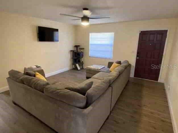 living room with ceiling fan, baseboards, and wood finished floors