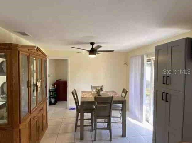 dining space featuring light tile patterned floors, ceiling fan, and visible vents