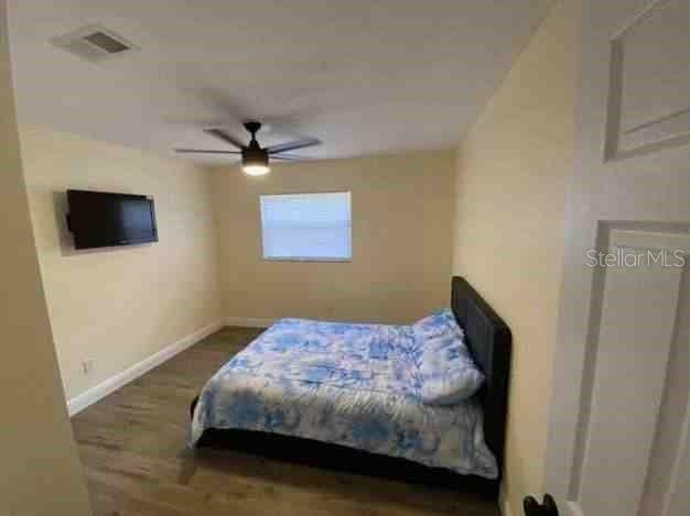 bedroom featuring visible vents, ceiling fan, baseboards, and wood finished floors