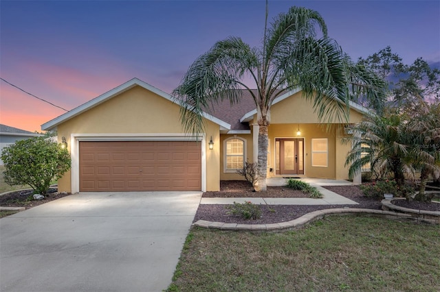 single story home featuring driveway, an attached garage, and stucco siding