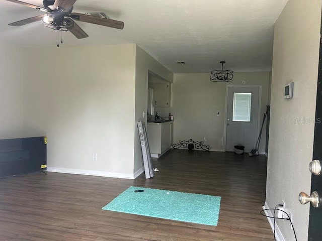 living room with wood finished floors, a ceiling fan, and baseboards