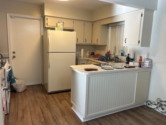 kitchen featuring white appliances, light countertops, a sink, and wood finished floors