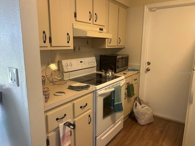 kitchen featuring under cabinet range hood, dark wood-type flooring, light countertops, stainless steel microwave, and white electric range oven