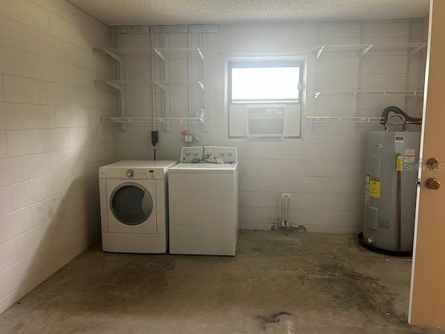 washroom featuring concrete block wall, water heater, washer and clothes dryer, and a textured ceiling