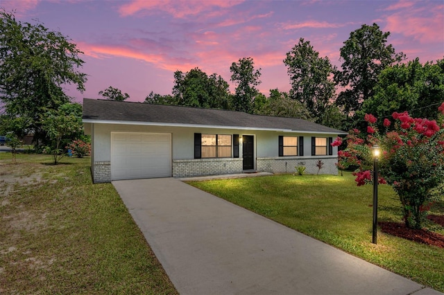 single story home with brick siding, a yard, stucco siding, concrete driveway, and a garage