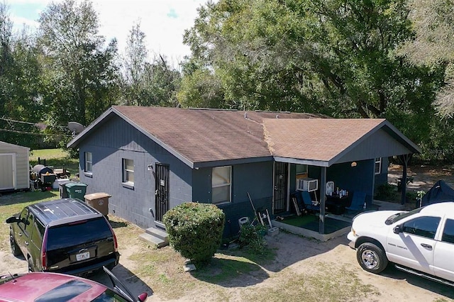 ranch-style house with a shingled roof, an outbuilding, concrete block siding, and cooling unit