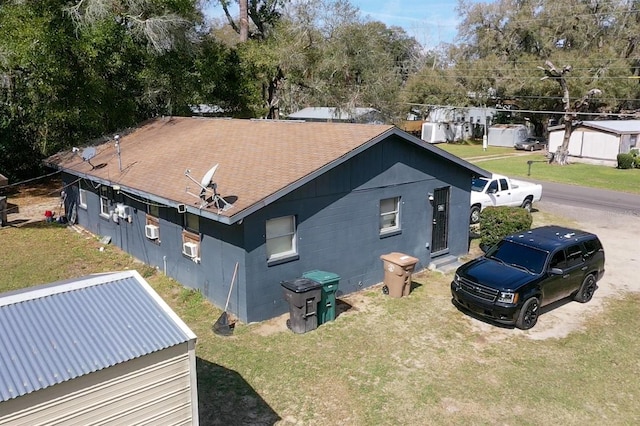 view of property exterior featuring a yard, concrete block siding, and roof with shingles