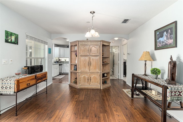 interior space with baseboards, visible vents, arched walkways, and dark wood-style flooring