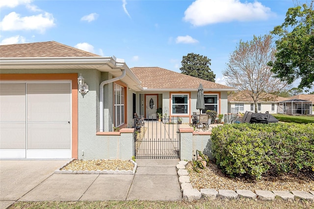 ranch-style home featuring a garage, roof with shingles, a gate, and stucco siding