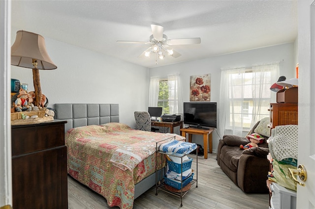 bedroom featuring multiple windows, light wood-style flooring, and a ceiling fan