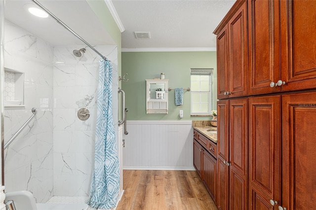 full bath featuring a wainscoted wall, wood finished floors, visible vents, and crown molding