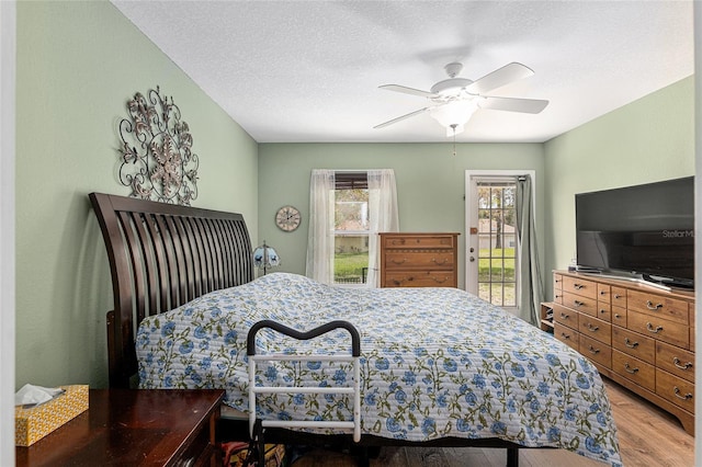 bedroom with access to exterior, ceiling fan, light wood-style flooring, and a textured ceiling