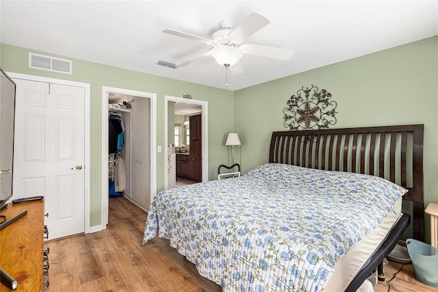 bedroom featuring a closet, visible vents, a walk in closet, and wood finished floors