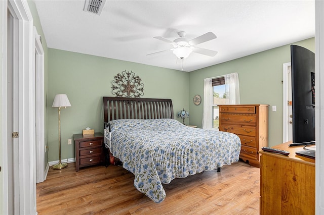 bedroom featuring ceiling fan, wood finished floors, visible vents, and baseboards