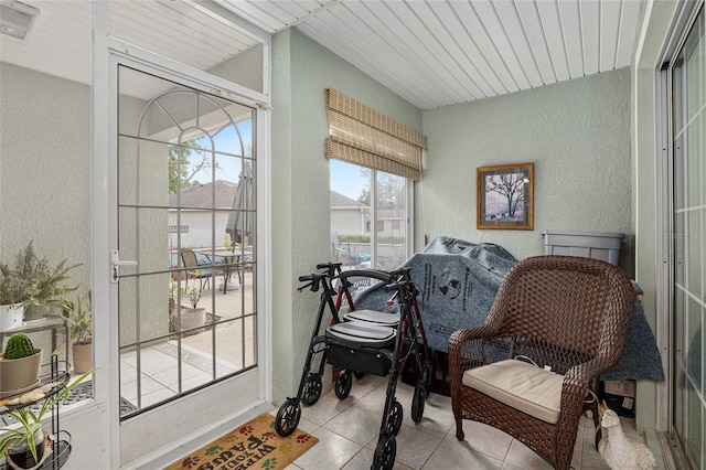 sitting room with light tile patterned floors, a textured wall, and a sunroom