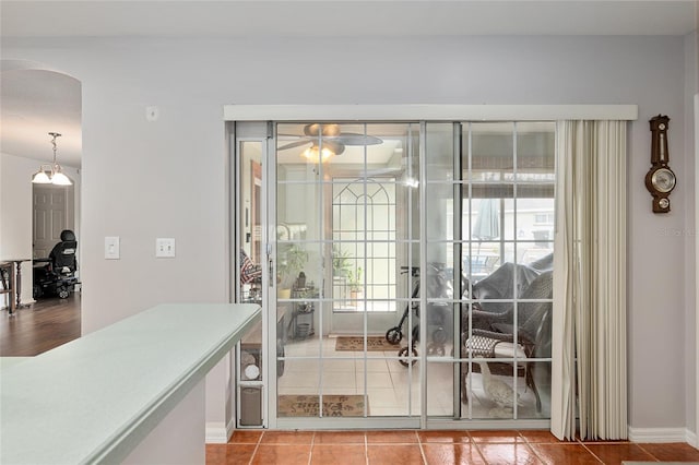 doorway to outside featuring arched walkways, a ceiling fan, and tile patterned floors