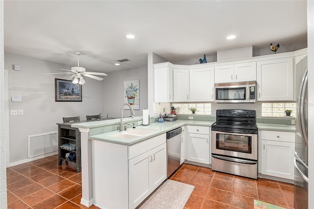 kitchen featuring stainless steel appliances, a peninsula, a sink, visible vents, and white cabinets