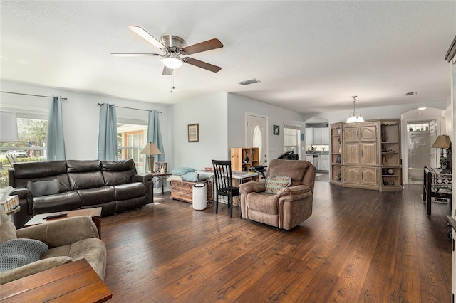 living area with arched walkways, ceiling fan, dark wood-type flooring, and visible vents