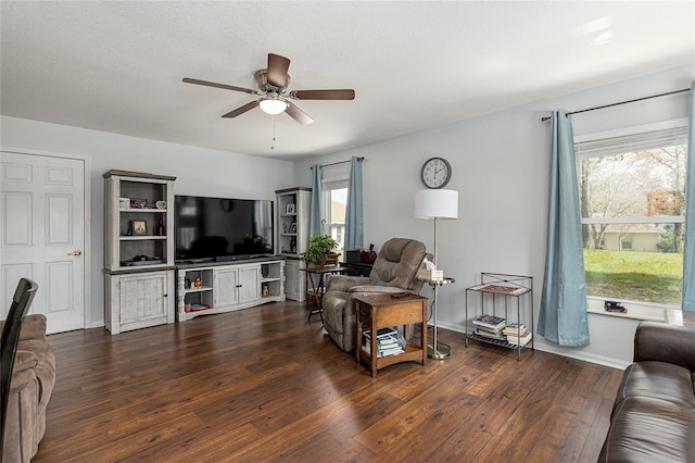 living room featuring dark wood-type flooring, baseboards, and a ceiling fan