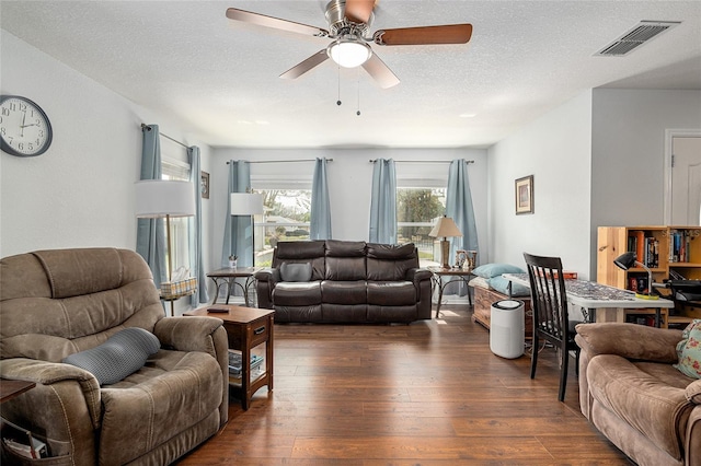 living area featuring a ceiling fan, wood-type flooring, visible vents, and a textured ceiling