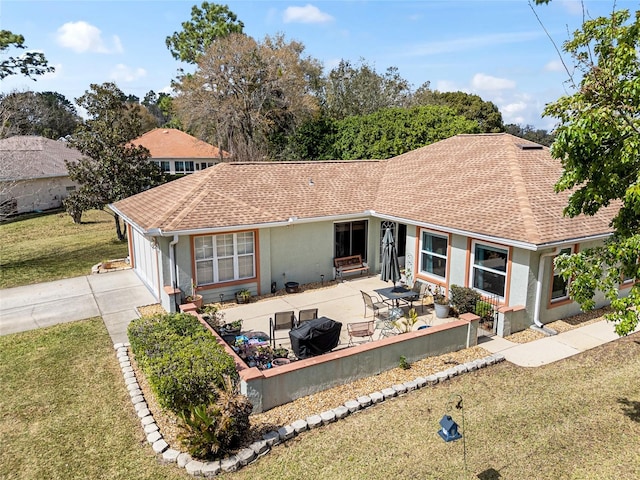 single story home with a shingled roof, concrete driveway, stucco siding, a front lawn, and a patio area