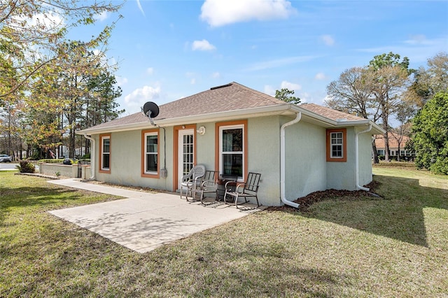 back of house with a yard, a shingled roof, a patio area, and stucco siding