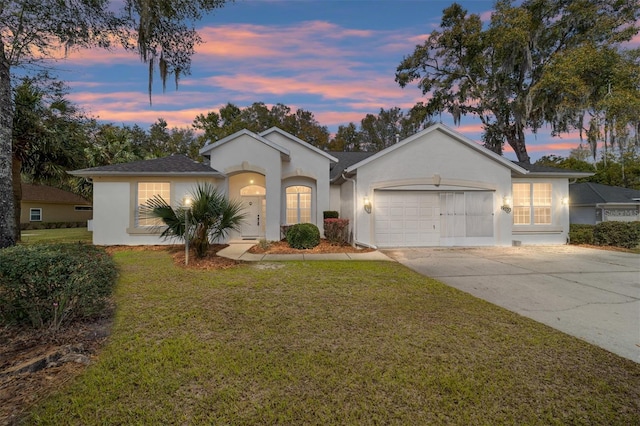 ranch-style house featuring a garage, concrete driveway, a front lawn, and stucco siding