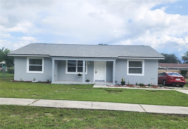 view of front of property featuring covered porch, roof with shingles, a front yard, and stucco siding