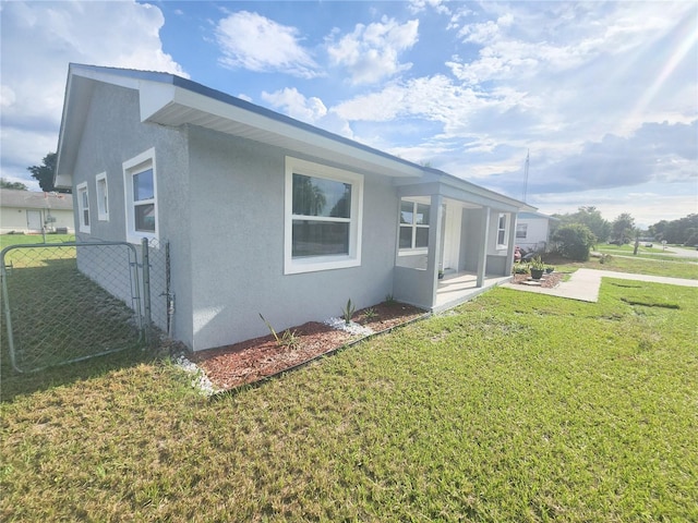 view of side of home with stucco siding, fence, a patio, and a yard