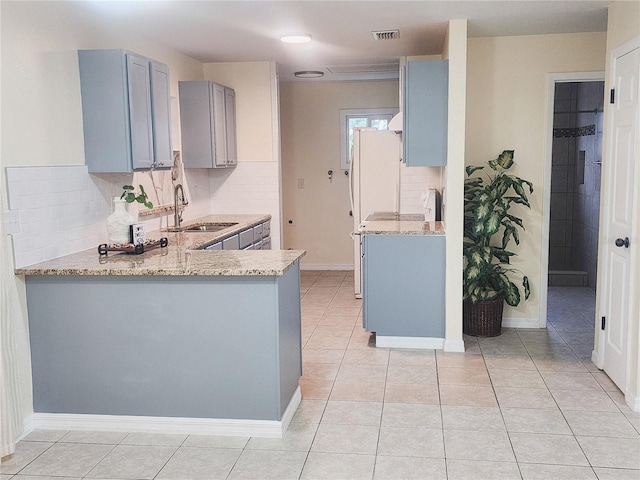 kitchen featuring light tile patterned floors, visible vents, light stone counters, gray cabinets, and a sink