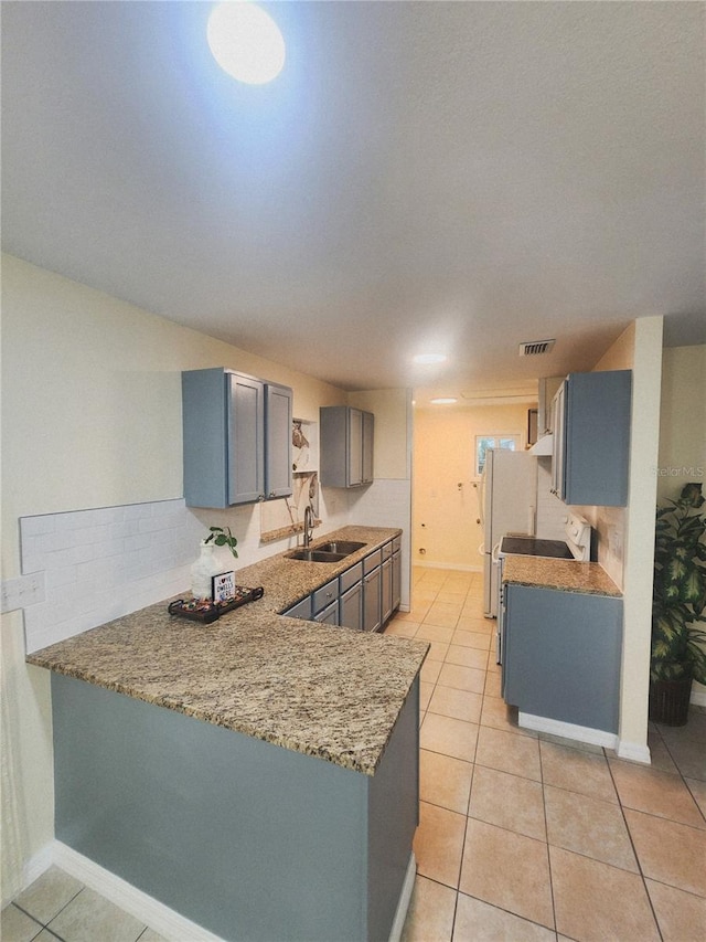 kitchen featuring gray cabinets, light tile patterned flooring, a sink, and a peninsula