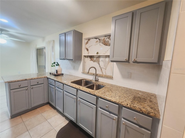 kitchen with gray cabinets, a sink, a peninsula, and backsplash