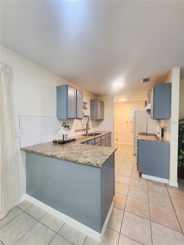 kitchen with a peninsula, light tile patterned flooring, visible vents, and decorative backsplash