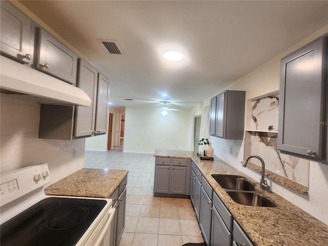 kitchen featuring decorative backsplash, gray cabinets, white electric stove, and a sink