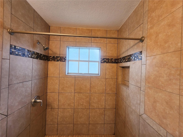 full bathroom with a tile shower and a textured ceiling