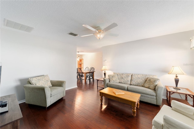 living room with a ceiling fan, visible vents, a textured ceiling, and hardwood / wood-style floors