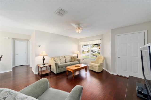 living area with a textured ceiling, wood finished floors, visible vents, and baseboards